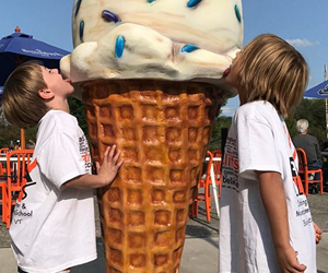 two kids licking a fake ice cream cone